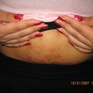 A woman with red nails is holding her stomach.