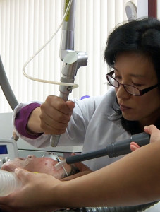 A woman is using an electric device to treat a patient.